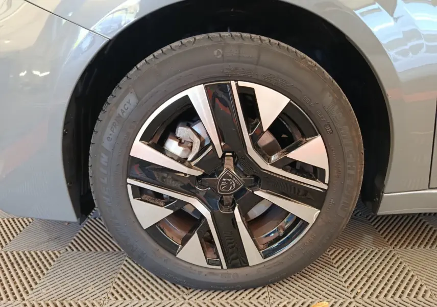 Gros plan sur la roue avant gauche gris foncé d'une Peugeot 208 PureTech 100 S&S Allure avec jante alliage noire et argent.