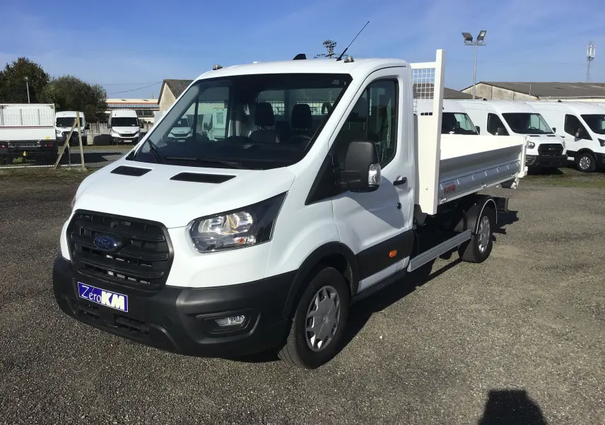 Vue 3/4 avant droite d’un Ford Transit Chassis Cabine blanc avec benne et bras de levage, stationné en extérieur.