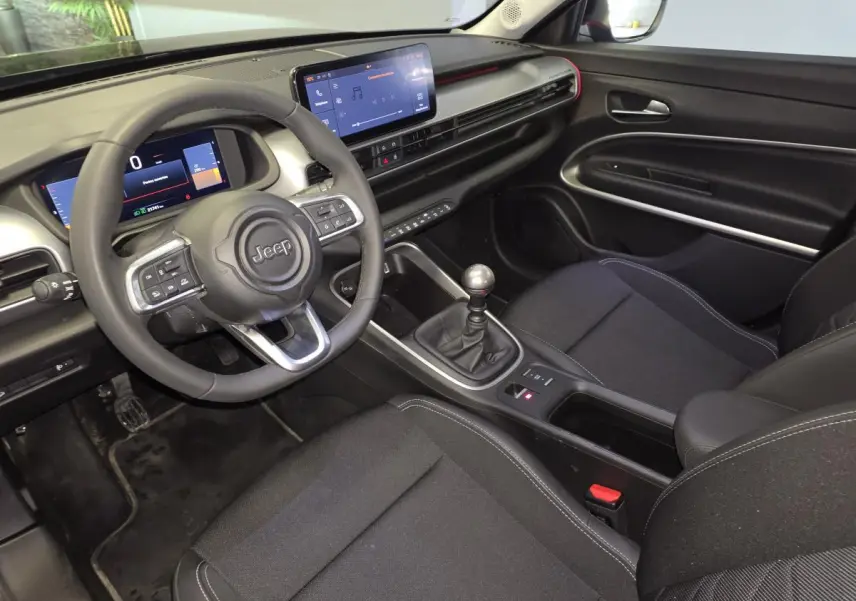 Vue intérieure côté conducteur du Jeep Avenger noir 2025, mettant en valeur le volant multifonction et la console centrale avec boîte manuelle.