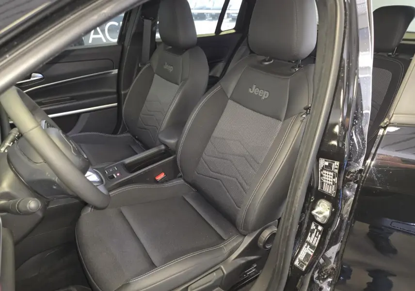 Vue intérieure côté conducteur du Jeep Avenger noir 2025, sièges tissu/TEP noirs avec logo Jeep brodé.