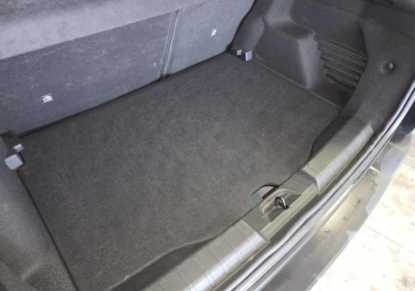 Vue plongeante sur le coffre noir du Jeep Avenger 2025, montrant le plancher de coffre modulable et tapis de sol.