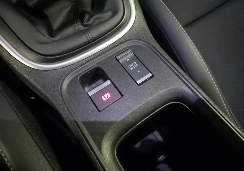 Gros plan sur la console centrale noire du Jeep Avenger 2025 montrant frein de stationnement électrique et bouton Drive Mode.