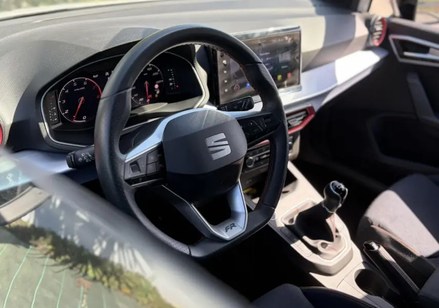 Vue intérieure centrée sur le volant FR et la console centrale avec levier de vitesse manuelle d'une SEAT Ibiza blanche.