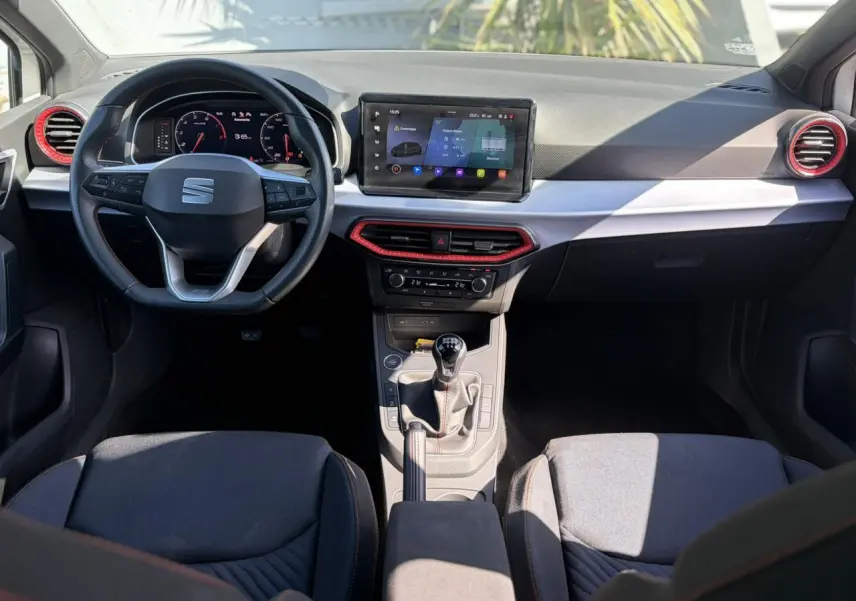Intérieur SEAT Ibiza TSI 115 FR 2025 vu de face, tableau de bord avec écran tactile et détails rouges autour des aérateurs.
