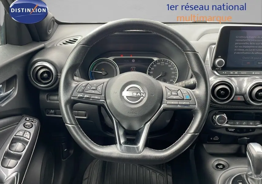 Vue centrée sur le volant noir du Nissan Juke Hybrid 2023 avec tableau de bord et écran tactile visible.