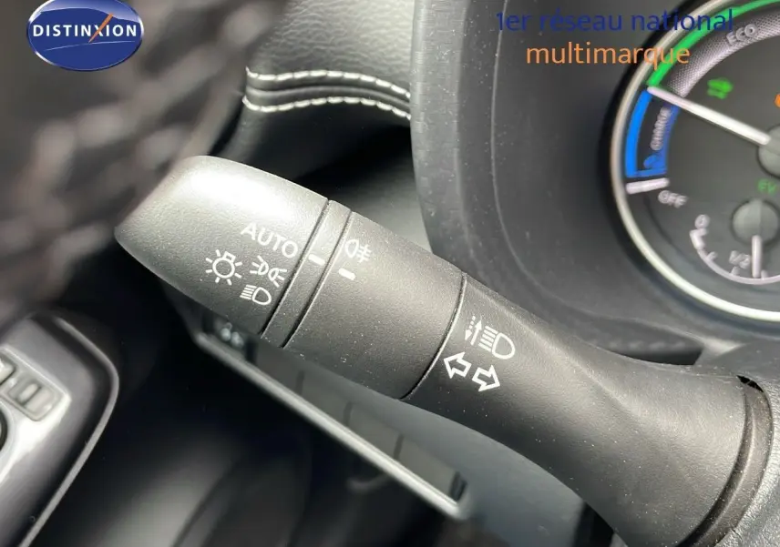 Gros plan sur la commande des feux et clignotants du Nissan Juke Hybrid 2023, intérieur noir avec tableau de bord partiel.