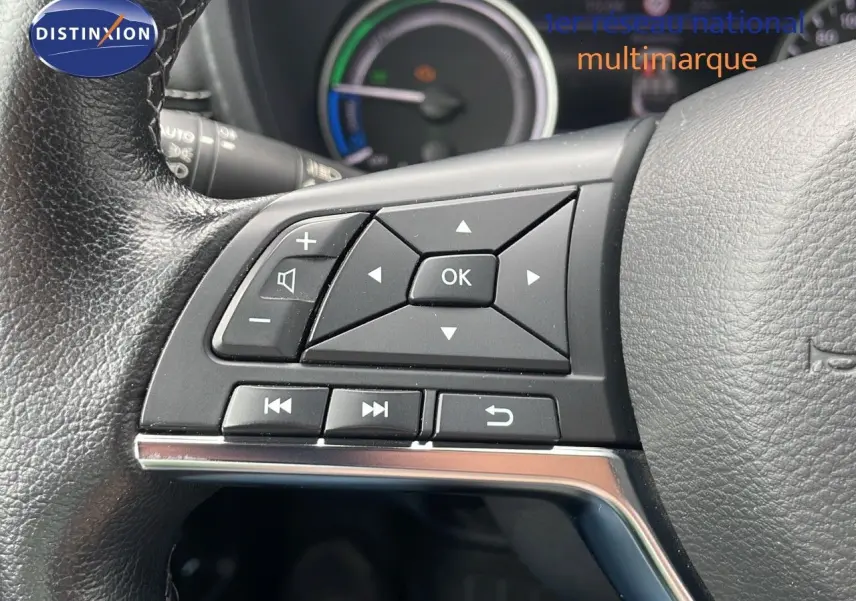 Gros plan sur les commandes multifonctions à gauche du volant en cuir du Nissan Juke Hybrid gris perle 2023.