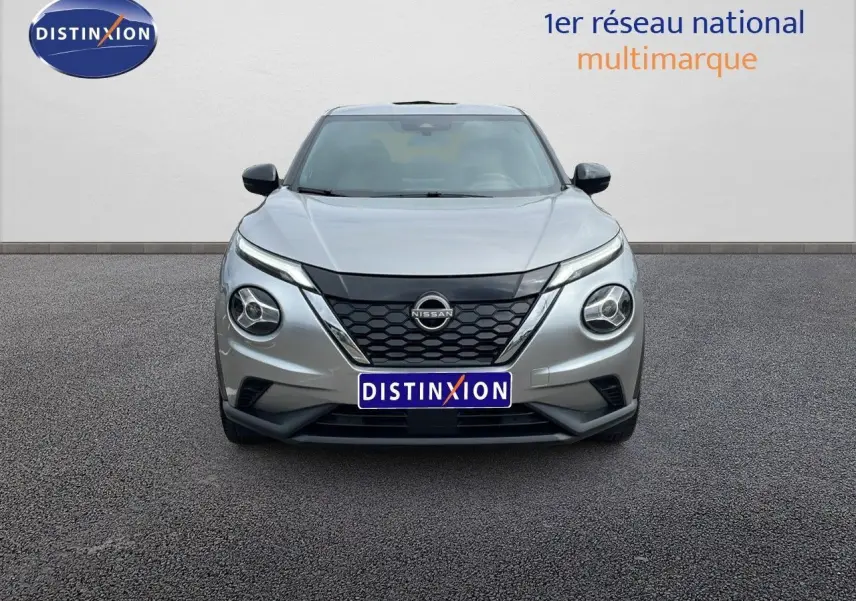 Vue frontale d'un Nissan Juke Hybrid gris perle métal avec calandre noire et phares ronds distinctifs.