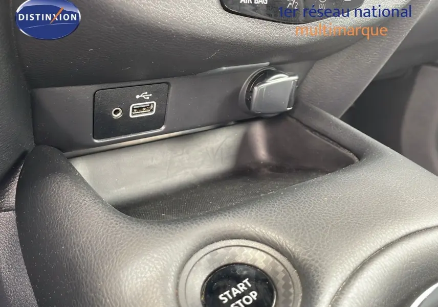 Gros plan sur la console centrale d'un Nissan Juke Hybrid gris perle, montrant le bouton start/stop et une prise USB.