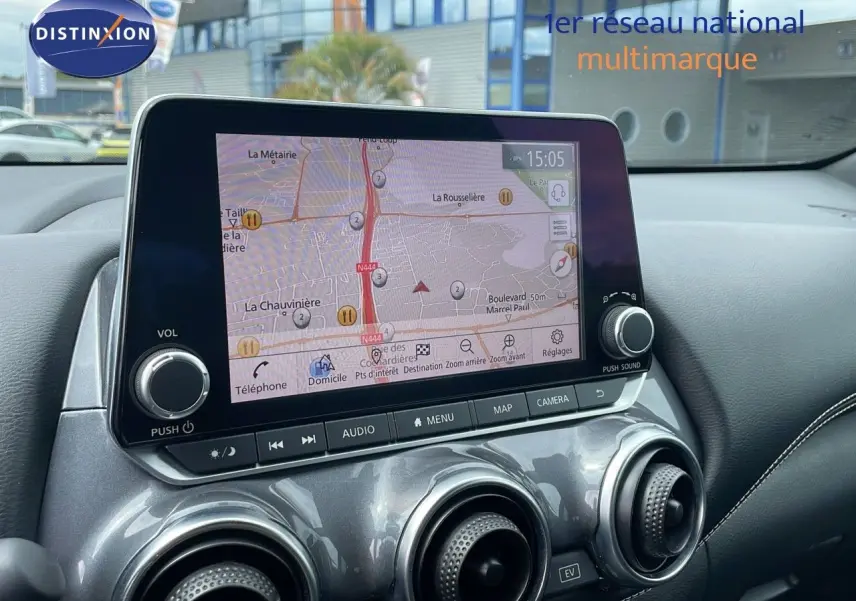 Tableau de bord du Nissan Juke Hybrid 2023 en gris perle, avec écran tactile affichant la navigation et aérateurs ronds métallisés.