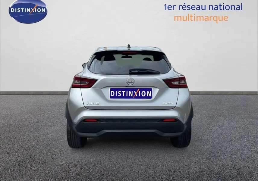 Vue arrière d'un Nissan Juke hybride gris perle métal avec logo Distinxion sur fond neutre.