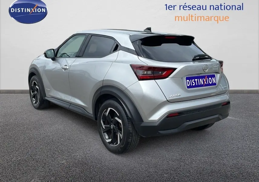 Nissan Juke Hybrid gris perle métal vu en 3/4 arrière côté gauche, avec jantes noires et toit noir.