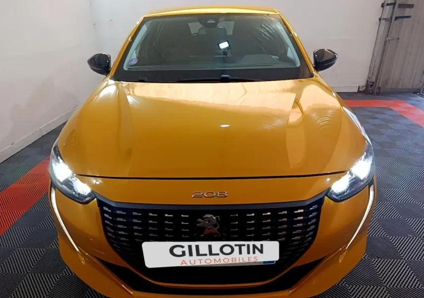Vue avant frontale d'une Peugeot 208 jaune avec phares LED allumés et calandre noire distinctive.