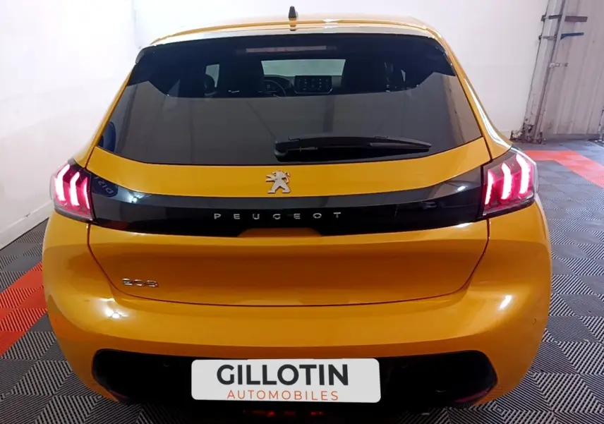 Vue arrière d'une Peugeot 208 jaune 2023 avec feux LED caractéristiques et bande noire brillante sur le hayon.