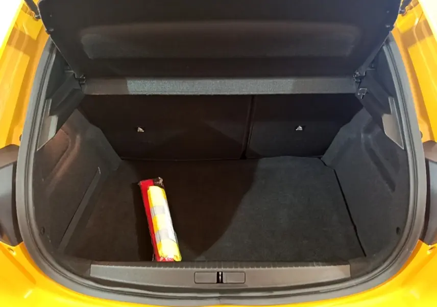 Coffre ouvert vu de l'arrière d'une Peugeot 208 jaune 2023, avec un triangle de signalisation visible à l'intérieur.