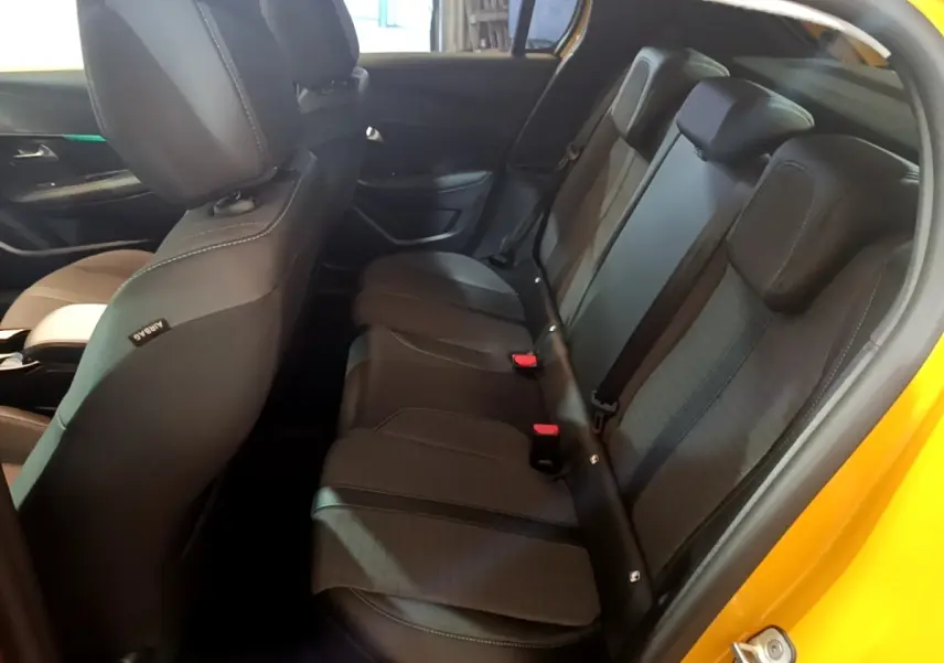 Vue intérieure côté droit montrant la banquette arrière noire de la Peugeot 208 jaune 2023 PureTech Allure Pack.