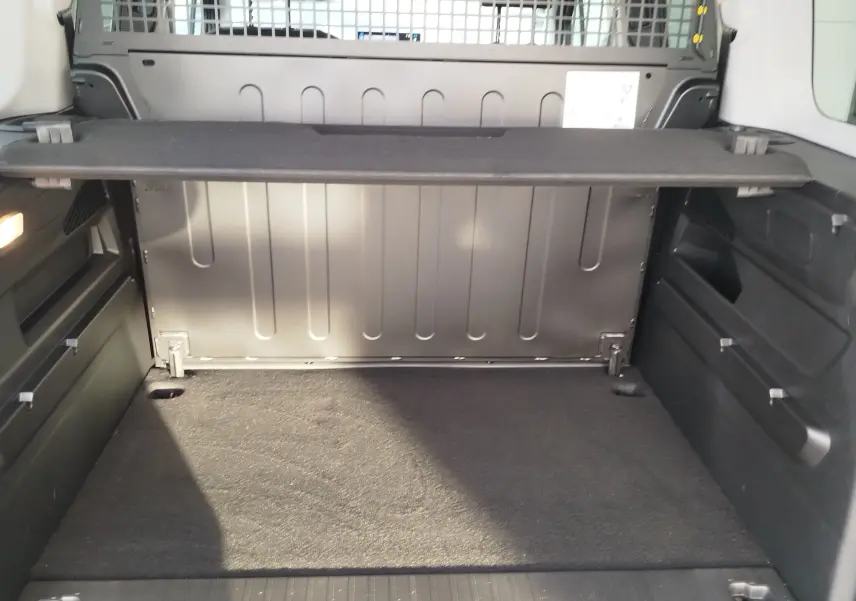 Coffre spacieux vu de l'intérieur arrière du Citroën Berlingo 2025 gris acier avec séparation rigide et revêtement noir.