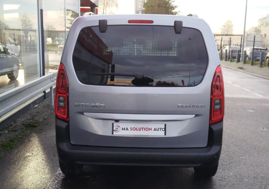 Vue arrière du Citroën Berlingo gris acier 2025 avec hayon vitré et feux arrière verticaux allumés.