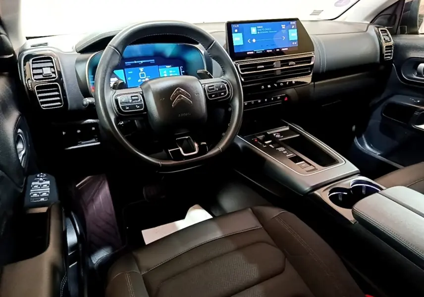 Intérieur noir du Citroën C5 Aircross hybride, vue avant centrée sur le volant multifonctions et l’écran tactile central.