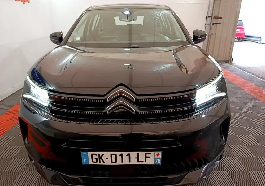 Vue avant d'une Citroën C5 Aircross hybride rechargeable noire avec phares LED allumés en intérieur.