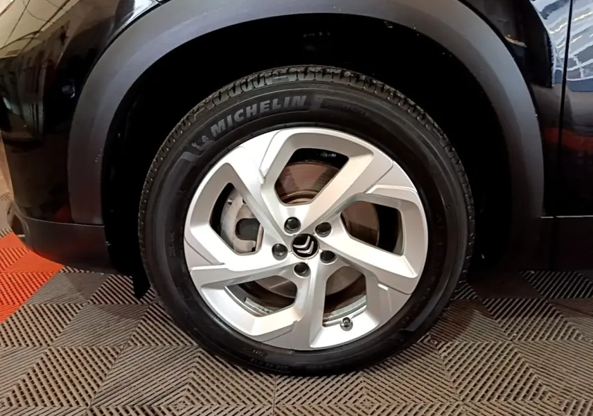 Gros plan sur la roue avant gauche noire du Citroën C5 Aircross hybride rechargeable avec jante argentée et pneu Michelin.