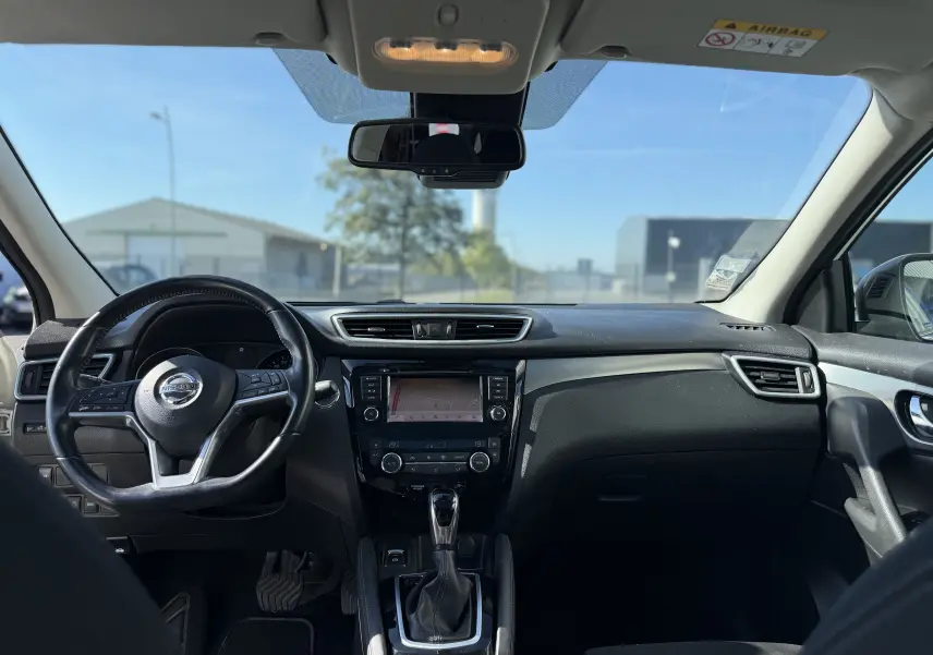 Intérieur du Nissan Qashqai blanc 2019 vu de face, tableau de bord noir avec écran tactile et volant multifonction.
