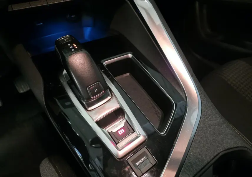 Gros plan sur la console centrale du Peugeot 5008 bleu, mettant en valeur le levier de vitesse automatique et bouton sport.