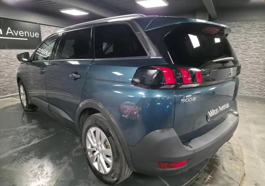 Vue 3/4 arrière droite du Peugeot 5008 bleu métallisé avec feux arrière à griffes et jantes alliage 17 pouces.