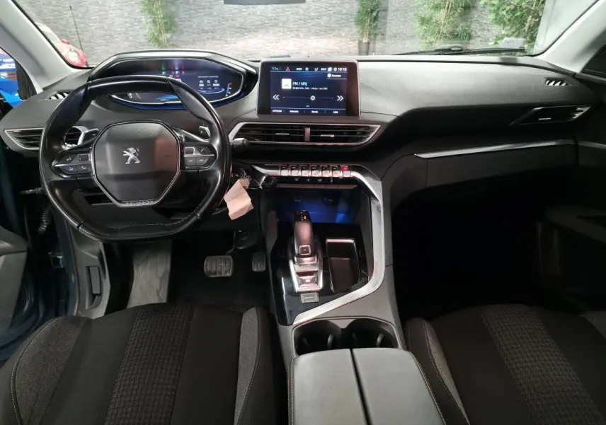 Intérieur du Peugeot 5008 bleu 2019 vu de face, tableau de bord moderne avec écran tactile et volant compact cuir.