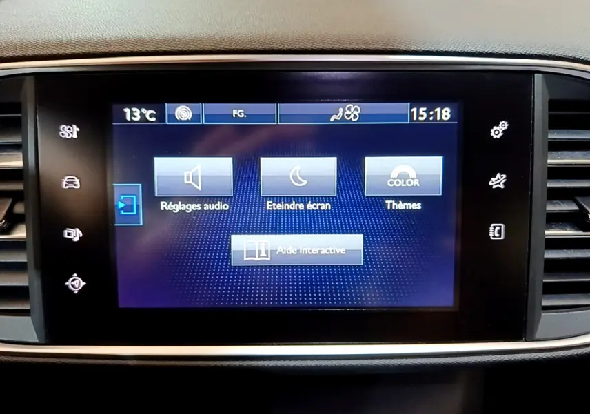 Écran tactile central de la Peugeot 308 gris foncé, affichant le menu des réglages audio et thèmes.