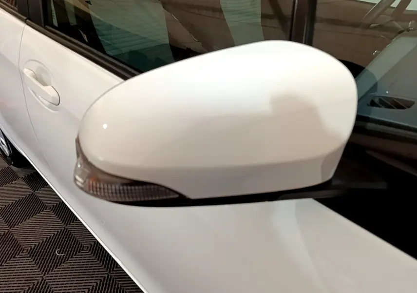 Gros plan sur le rétroviseur côté gauche blanc d'une Toyota Yaris hybride 2019, avec la portière visible en arrière-plan.