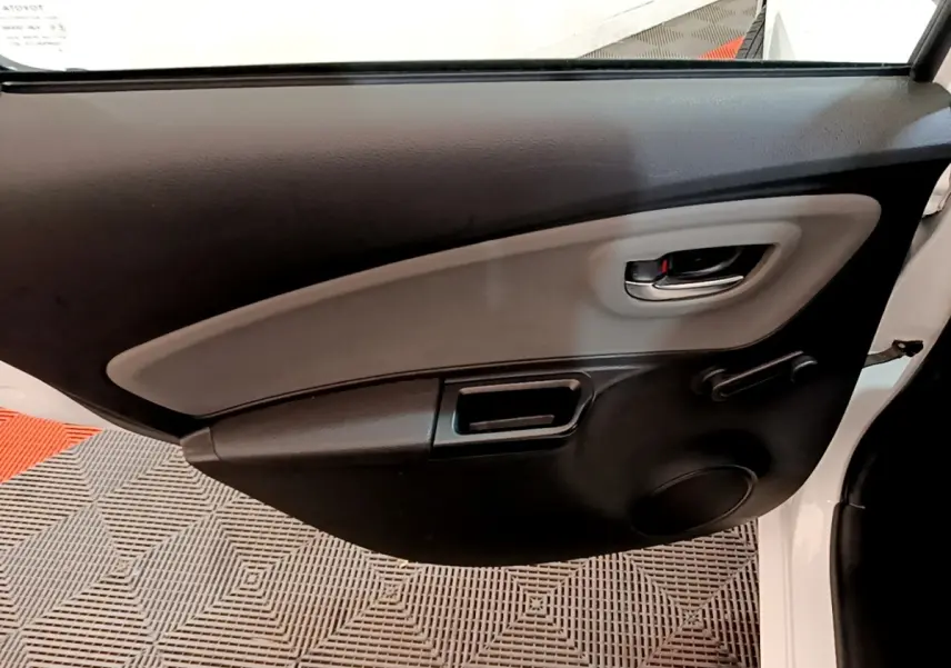 Vue intérieure côté gauche de la porte arrière blanche de la Toyota Yaris 2019 avec poignée et commande de vitre manuelle.