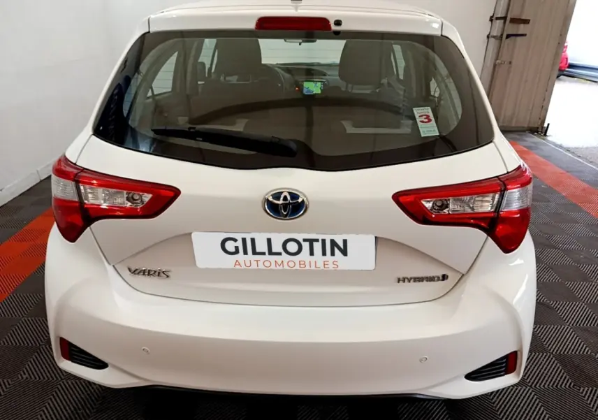 Vue arrière d'une Toyota Yaris blanche hybride 2019, avec feux arrière distinctifs et logo Toyota visible.