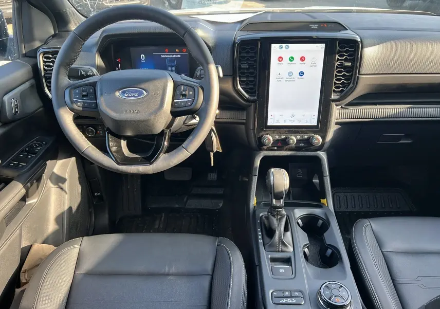 Vue intérieure du poste de conduite du Ford Ranger 2025 avec volant multifonction, écran tactile vertical et levier de boîte automatique.