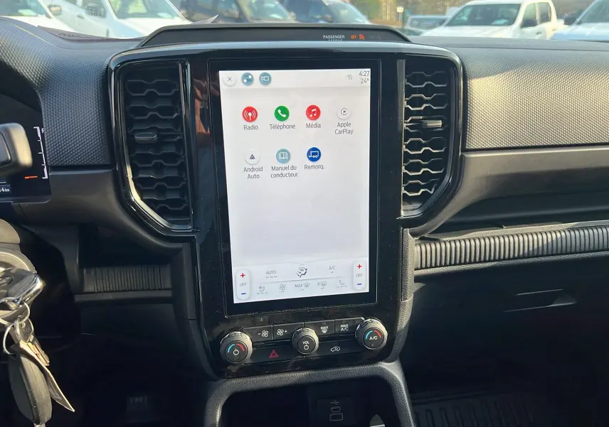 Vue intérieure du tableau de bord du Ford Ranger 2025 avec écran tactile central et commandes climatisation visibles.