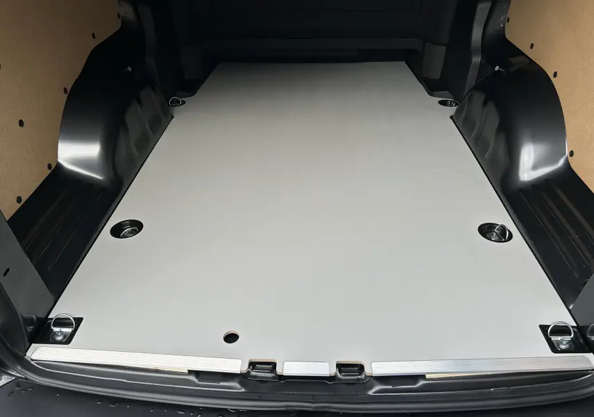 Vue arrière du coffre spacieux du Citroën Jumpy cabine approfondie gris titane avec plancher plat et anneaux d’arrimage.
