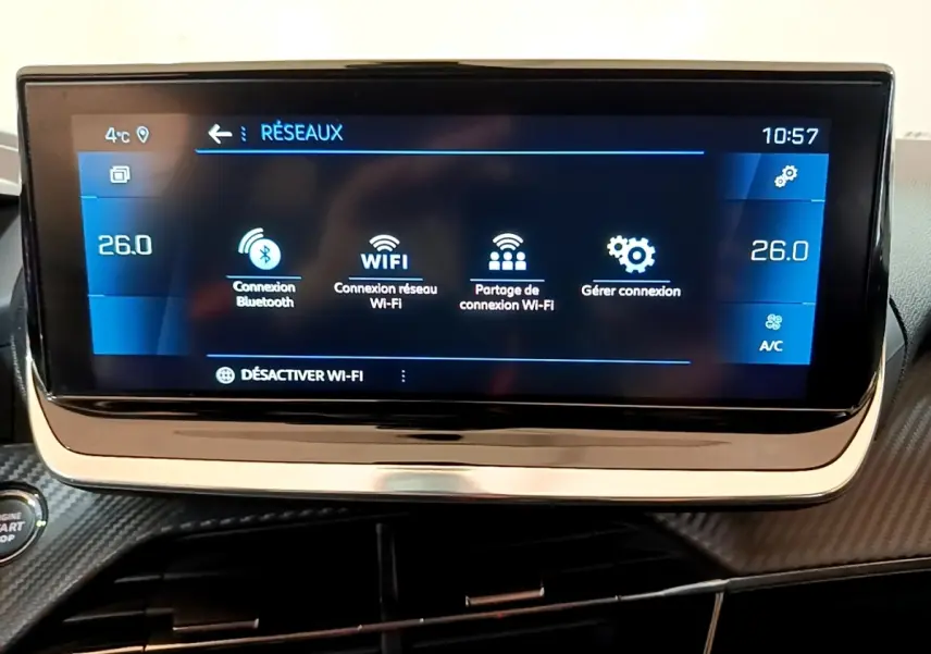 Écran tactile central 10 pouces du tableau de bord de la Peugeot 208 blanche, affichant les options réseau Wi-Fi et Bluetooth.