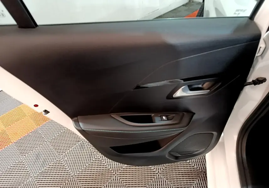 Vue rapprochée de la porte arrière droite blanche d'une Peugeot 208 2021 avec garniture intérieure noire et poignée argentée.
