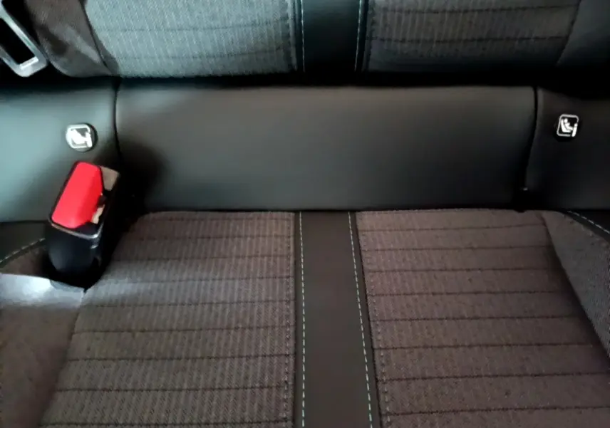 Gros plan sur la banquette arrière noire et grise de la Peugeot 208, avec ceinture de sécurité rouge visible à gauche.