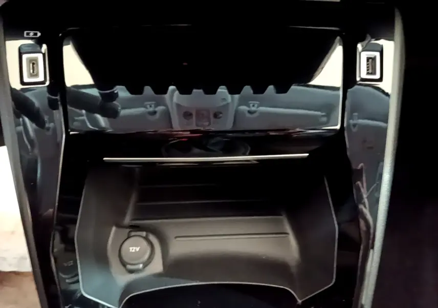 Vue rapprochée de la console centrale noire avec prise 12V et ports USB de la Peugeot 208 blanche 2021.