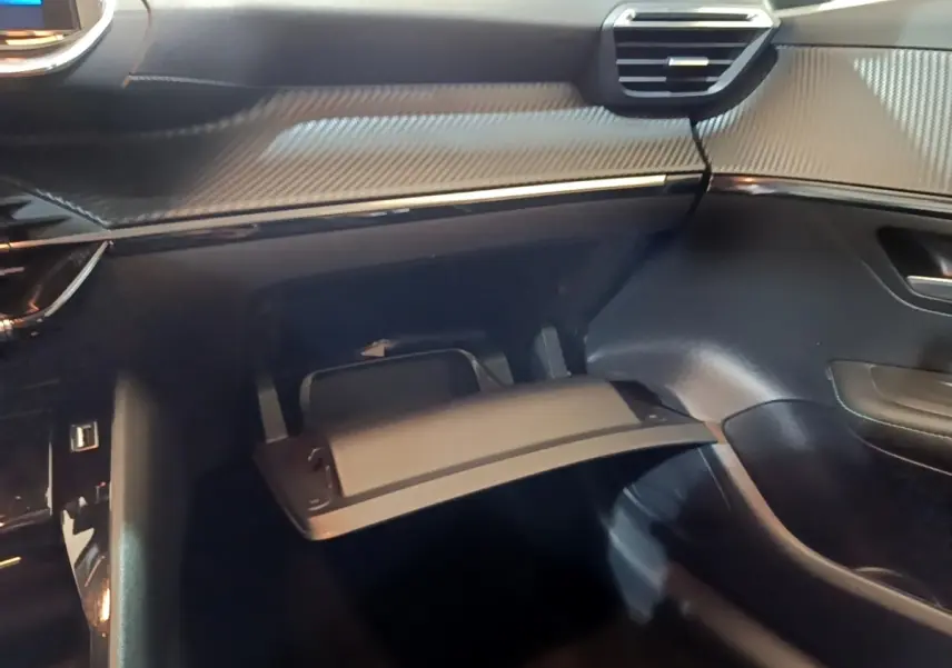 Vue intérieure côté passager du Peugeot 208 blanc 2021, avec boîte à gants ouverte et tableau de bord noir texturé.