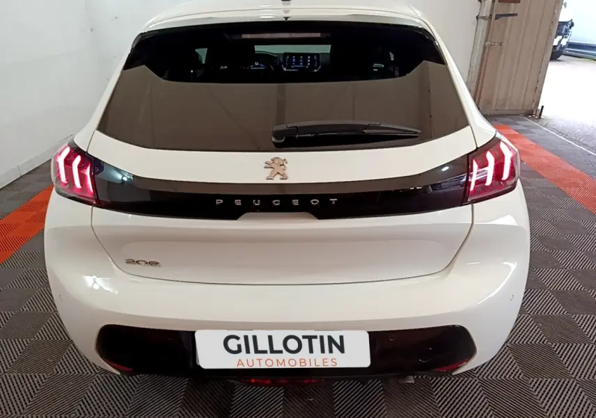 Vue arrière d'une Peugeot 208 blanche de 2021 avec feux LED distinctifs et logo noir brillant au centre.
