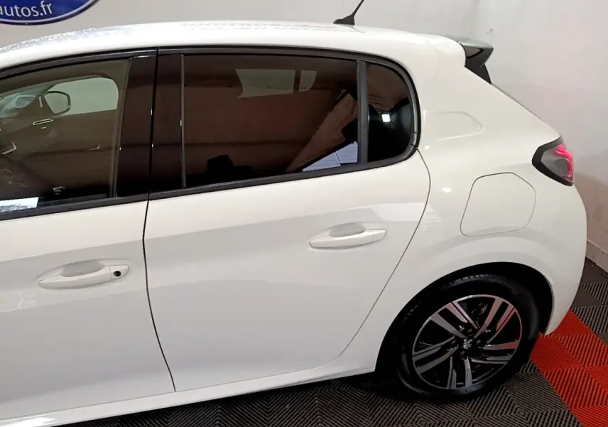 Vue latérale droite d'une Peugeot 208 blanche de 2021, avec vitres teintées et jantes alliage noires.