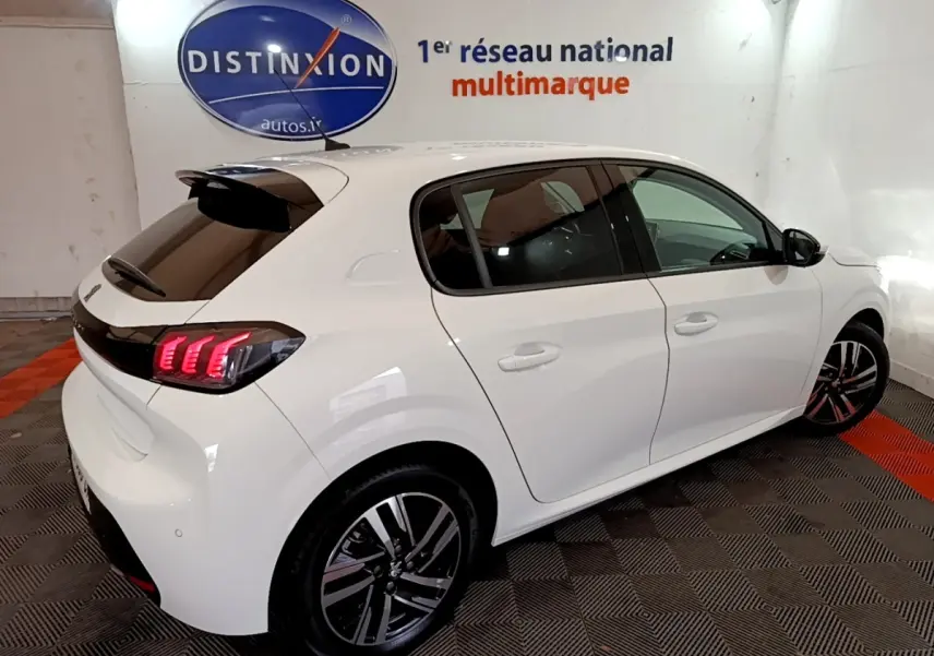 Vue 3/4 arrière droite d'une Peugeot 208 blanche avec feux arrière LED et jantes alliage distinctives.