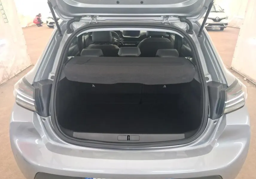 Vue arrière ouverte sur le coffre d'une Peugeot 208 gris clair 2024, mettant en valeur l'espace de chargement et les feux arrière.