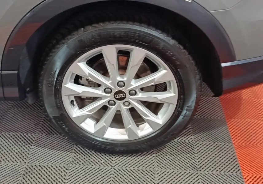 Gros plan sur la roue avant droite grise d’un Audi Q3 Sportback 45 TFSI e avec jante argentée multifacettes.