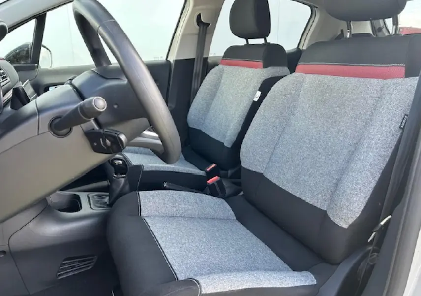 Vue intérieure côté conducteur de la Citroën C3 2021, sièges tissu gris clair avec bande rouge et noir.