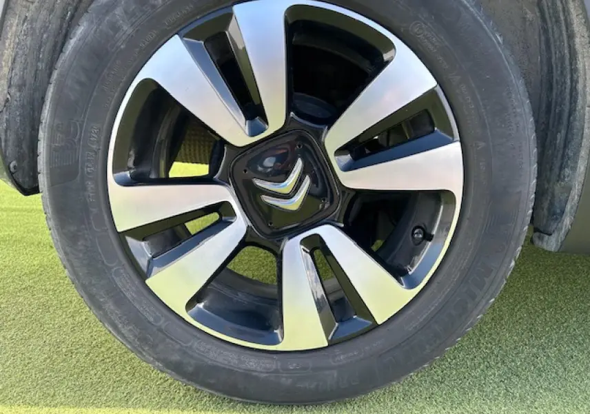 Gros plan sur la jante alliage diamantée 16 pouces noire et argentée d'une Citroën C3 sable métal.