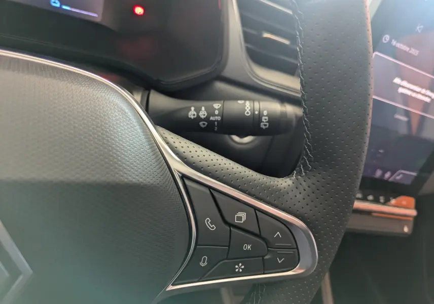 Gros plan sur le volant en cuir perforé avec commandes multifonctions du Renault Captur E-Tech Gris Cassiopée 2025.