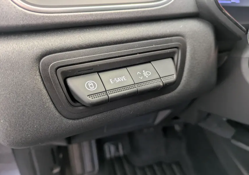 Gros plan sur les boutons de commande E-SAVE et réglage des phares dans l'habitacle du Renault Captur gris Cassiopée 2025.